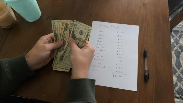 Extreme Frugal Living: hands counting cash on a kitchen table next to a handwritten monthly budget with expenses listed