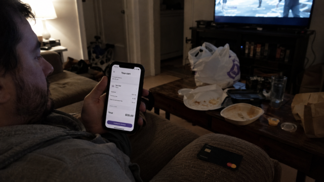person sitting on couch looking at food delivery person sitting on couch looking at food delivery app on phone with credit card in hand late at night