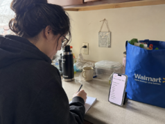 15 Ways to Save Money on Groceries: Ranked by Actual Dollar Impact person writing grocery list at kitchen counter with phone showing weekly budget