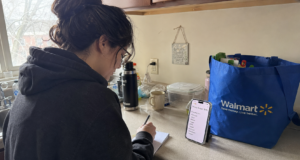 15 Ways to Save Money on Groceries: Ranked by Actual Dollar Impact person writing grocery list at kitchen counter with phone showing weekly budget