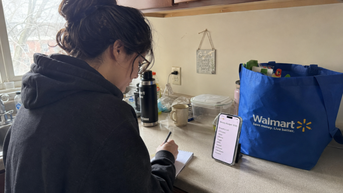 15 Ways to Save Money on Groceries: Ranked by Actual Dollar Impact person writing grocery list at kitchen counter with phone showing weekly budget